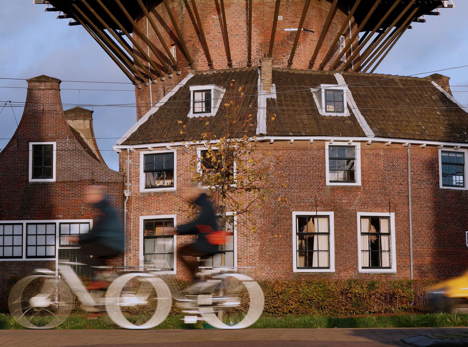 Fietsers met bewegingsonscherpte voor een molen in Delft