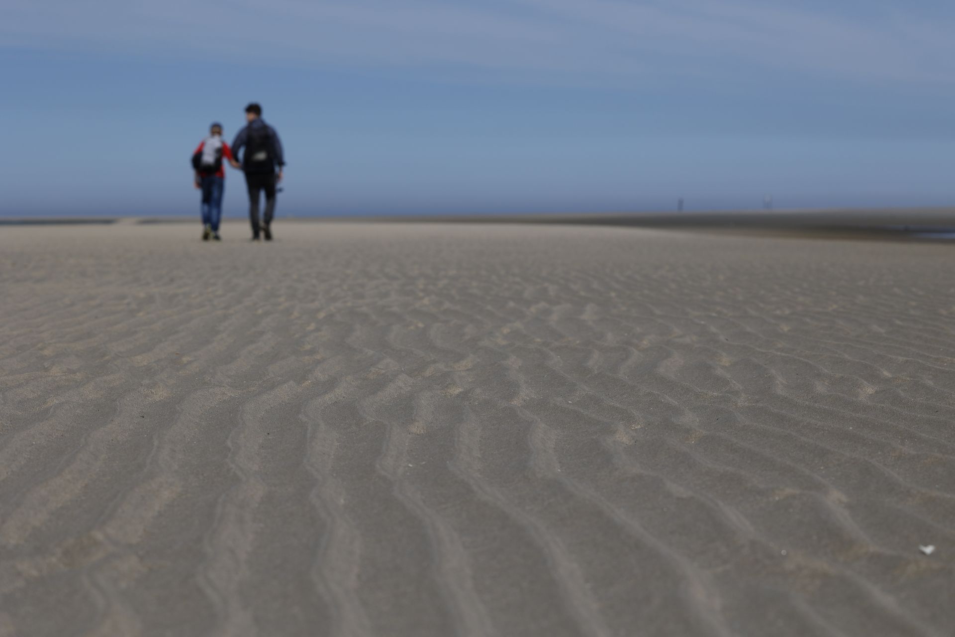 Breed Noordzeestrand met golven en wandelaars, Terschelling